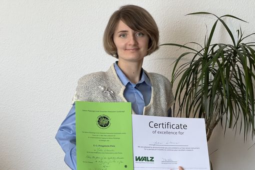 Auf dem Farbfoto hält Julia Lihanova ihre Auszeichnung in beiden Händen. Die Auszeichnung ist der Pringsheim Preis.