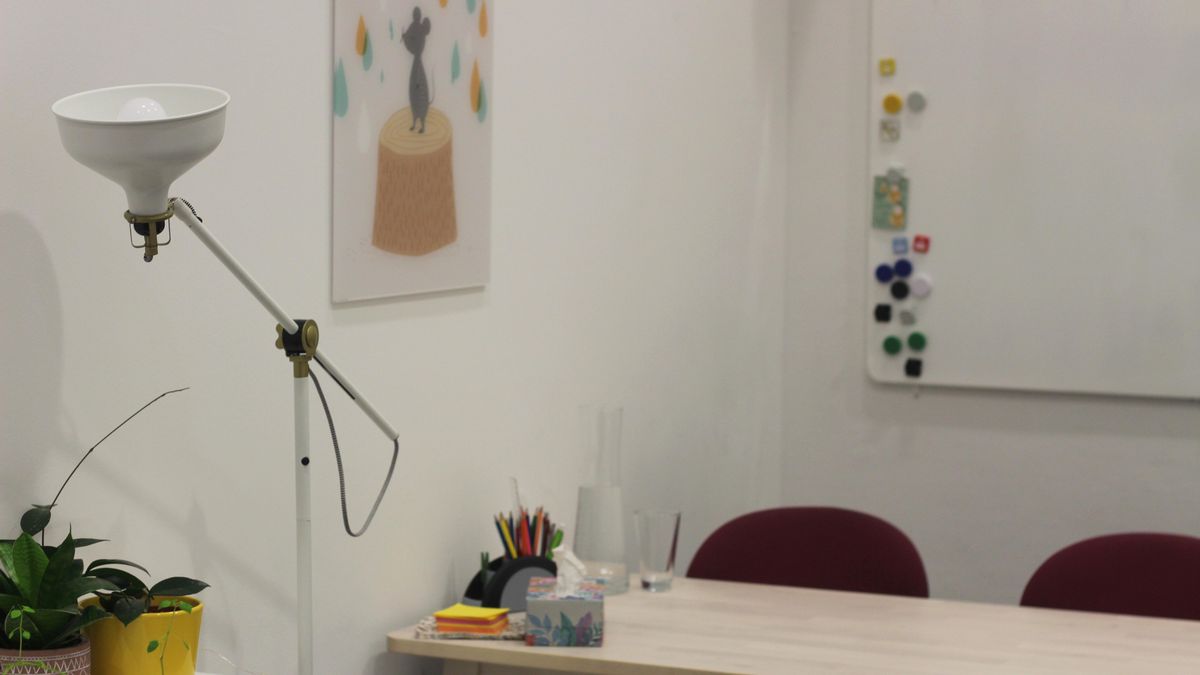 enlarge the image: Photo of a therapy room from inside with a table and a floor lamp.