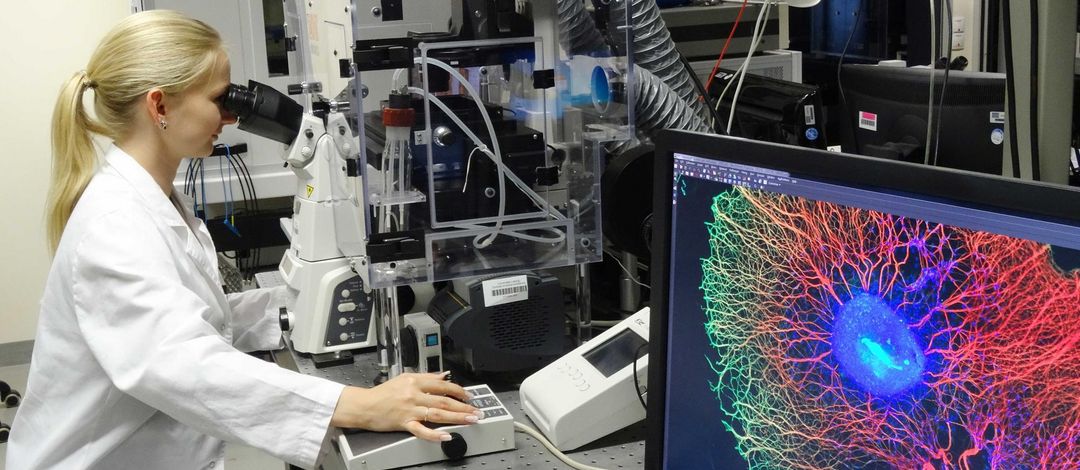 Foto: Eine Frau im Laborkittel sitzt vor einem Superresolutionsmikroskop am Biotechnologisch-Biomedizinischen Zentrum