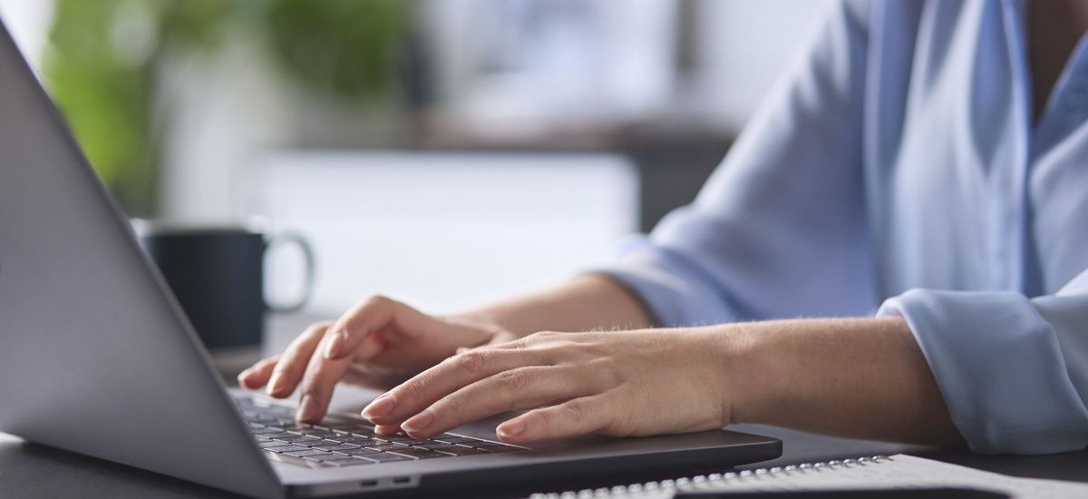Person schreibt etwas an einem Laptop