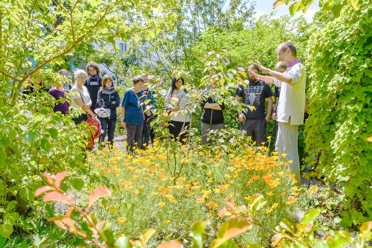 Eine Gruppe von Besuchern nimmt an einer Führung des Kustos Dr. Martin Freiberg im Freigelände des botanischen Gartens teil.