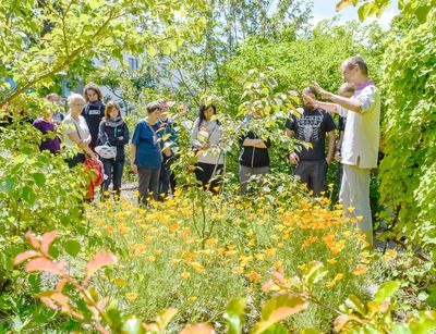 Eine Gruppe von Besuchern nimmt an einer Führung des Kustos Dr. Martin Freiberg im Freigelände des botanischen Gartens teil.