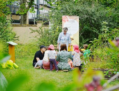 Die Projektleiterin des Projektes Kindergarten - Gartenkinder erklärt einer Gruppe Kinder das Programm und den Ablauf des Tages. Die Kinder sitzen im Kreis. Foto: Dorett Bothmann