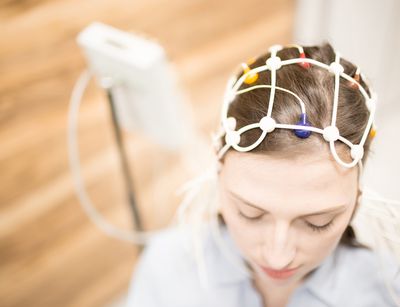 Probandin mit EEG-Haube und Elektroden auf dem Kopf und EEG-Verstärker