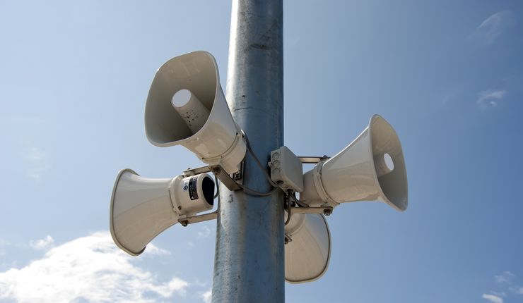 Vier Megaphone hängen an einer Stange.