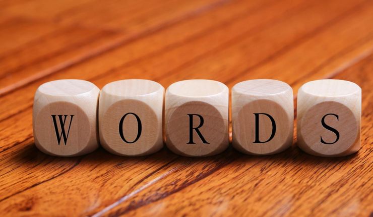 Fünf Würfel aus Holz liegen nebeneinander auf einem Tisch und bilden den Schriftzug "Words".