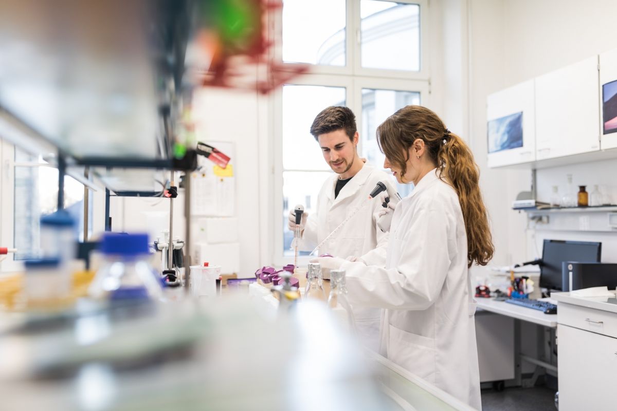 Ein Mann und eine Frau stehen im Labor und arbeiten mit wissenschaftlichen Instrumenten.